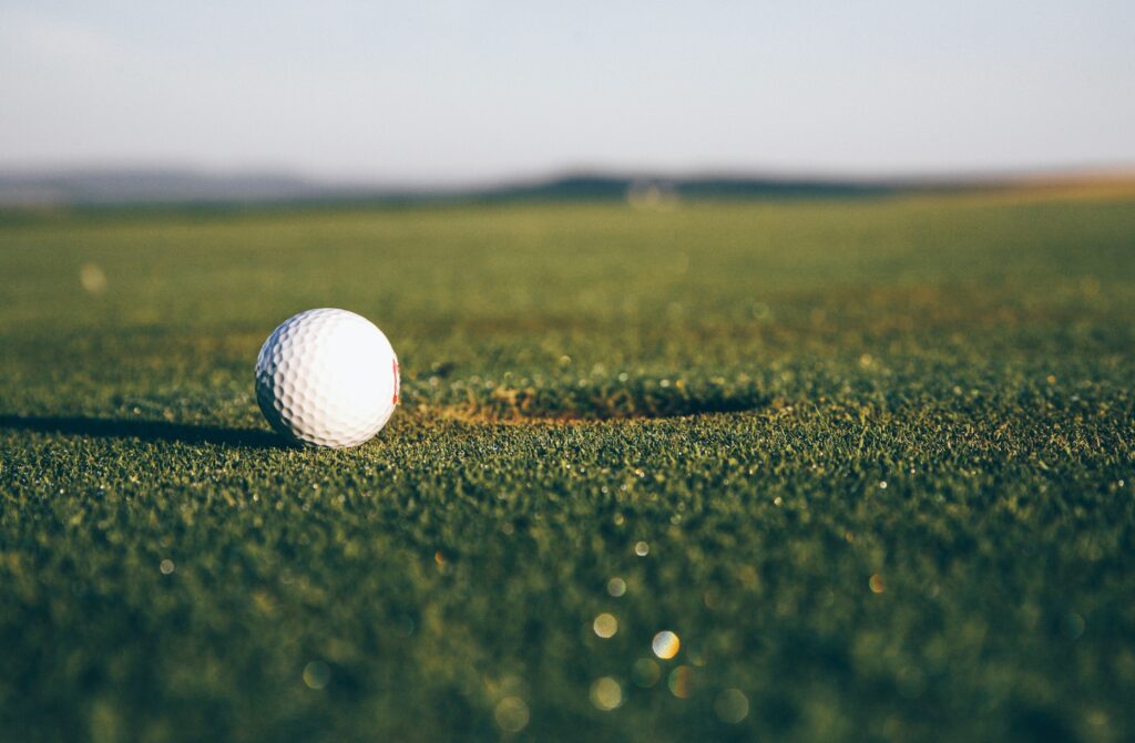Close-up of a white golf ball resting on green grass on a golf course.